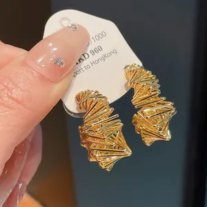 Detailed view of gold-plated irregular geometric twisted wire earrings on a white card.