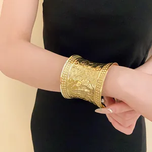 Detail view of wide gold-plated cuff bracelet with intricate floral embossed pattern