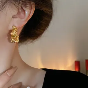 Detailed view of irregular gold plated wire earrings showing elegant aesthetic on ear