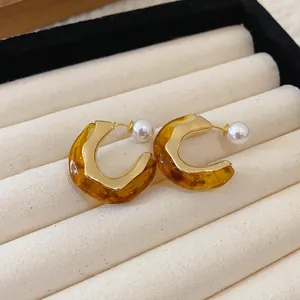 Macro view of French retro amber resin C-shaped earrings with pearl accents in jewelry box