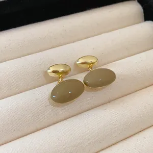 Close-up of elegant French retro coffee-colored oval drip oil earrings on velvet tray