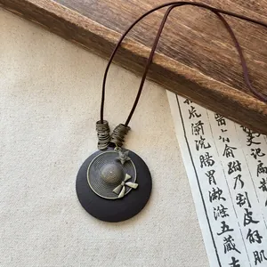 Detailed view of a vintage Zen style necklace featuring a round pendant with a brass hat motif