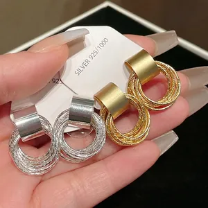 Orecchini geometrici minimalisti a cerchio multiplo in oro e argento con ago in argento.