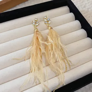 Detail view of French retro Maillard brown feather drop earrings with floral studs.