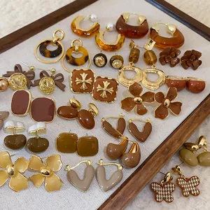 Detail view of various vintage coffee-toned earrings in floral and geometric styles on a tray