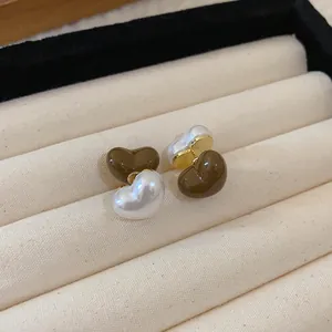 Close-up of retro Maillard style heart stud earrings with coffee and pearl finish.