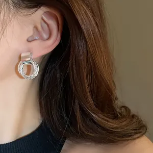Primo piano di un orecchino a cerchio geometrico argento minimalista su una modella