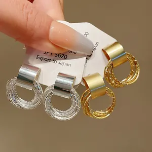Dettaglio ravvicinato di orecchini a cerchio geometrici con finiture in oro e argento
