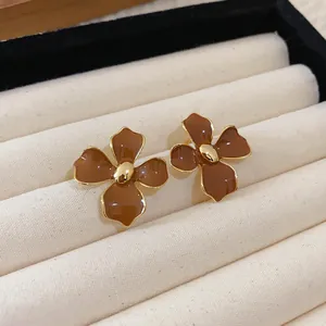 Macro close-up detail showing the vintage Maillard coffee-colored flower enamel earrings on tray