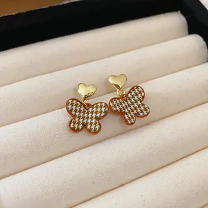 Detailed macro view of retro butterfly earrings with brown houndstooth and heart studs.