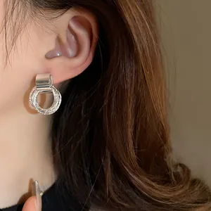 Dettaglio ravvicinato di orecchini circolari geometrici minimalisti in argento all'orecchio