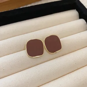 Close-up of elegant vintage coffee enamel stud earrings with gold-tone metal edges.