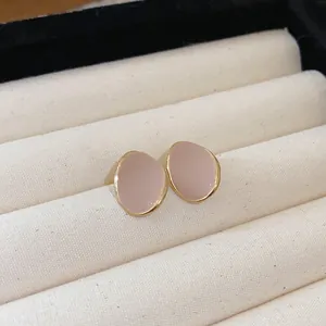 Detailed macro shot of vintage nude enamel stud earrings with gold-tone borders