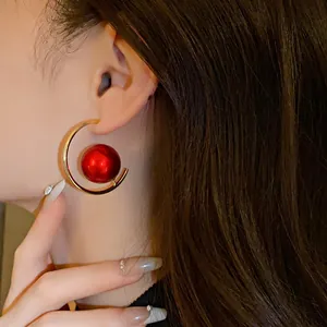 Elegant gold C-shaped hoop earring with metallic red pearl detail on Asian model