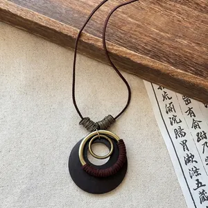 Vintage ethnic style long necklace with dark wood and brass circular pendants.