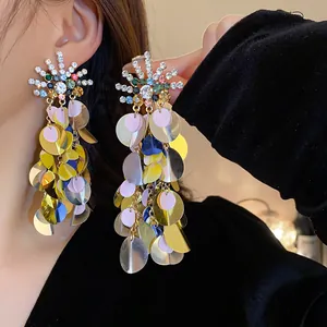 Detailed macro shot of exaggerated colorful sequin dangle earrings with rhinestone top