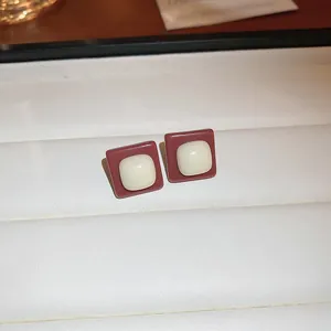 Close-up detail of retro square stud earrings with brown oil-drip and cream center