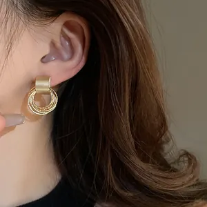 Primo piano di orecchini a cerchio intrecciati dorati indossati da una modella asiatica