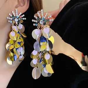 Close-up of oversized colorful sequin earrings with sparkling sunburst rhinestone studs
