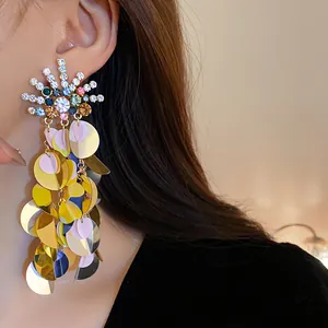 Close-up of oversized sparkling rhinestone earrings with colorful sequin tassels for vacation
