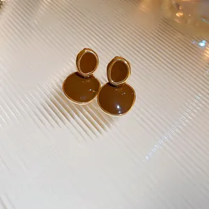 Close-up of French retro brown enamel earrings with gold-tone metal borders
