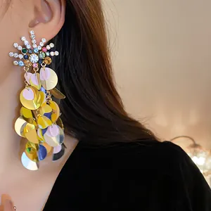 Close-up view of oversized rhinestone sunburst earrings with colorful dangling sequins.