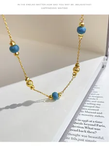 Macro detail view of vintage style necklace with gold beads and blue stones on book.
