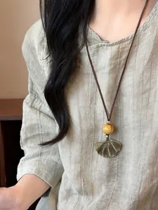Detailed macro view of a vintage Zen style ginkgo leaf pendant necklace with a wooden bead