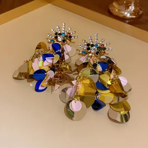Close-up of vibrant multicolored sequin tassel earrings with rhinestone sunburst