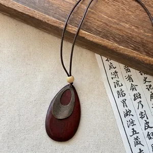 Close-up detail of retro Zen style teardrop wooden necklace with antique bronze textured overlay