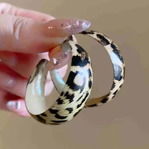 Close-up detail of retro fashion leopard print wide C-shaped hoop earrings for women