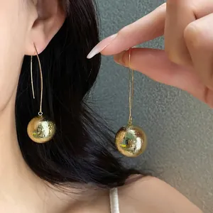 Oversized textured gold sphere drop earrings showing a bold statement fashion look