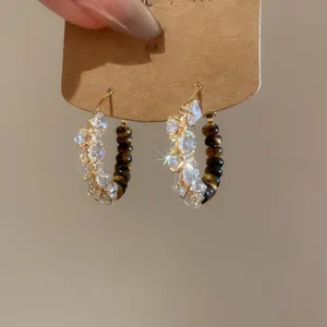 Detailed close-up showing the tiger eye beads and raw crystals on gold-plated hoop earrings