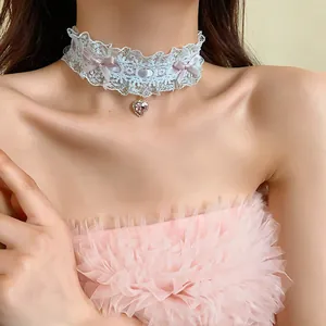 Dettaglio di un elegante choker in pizzo bianco con fiocchi rosa e ciondolo a cuore