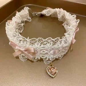 Vista dettagliata di un elegante choker in pizzo bianco con fiocchi rosa e ciondolo a cuore