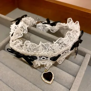 Dettaglio del girocollo in pizzo con fiocchi neri e ciondolo a cuore con strass.