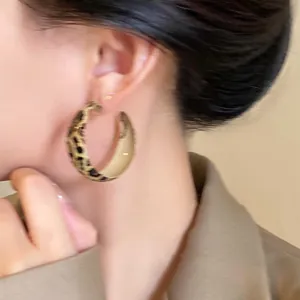 Close-up detail of a woman wearing retro leopard print geometric hoop earrings
