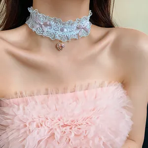 Primo piano di un choker in pizzo bianco con fiocco viola e ciondolo a cuore rosa con strass