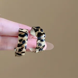 Detail shot of vintage leopard print hoop earrings with wavy edges and glossy finish.