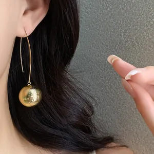 Detailed macro shot of textured golden ball drop earrings showing elegant ear styling