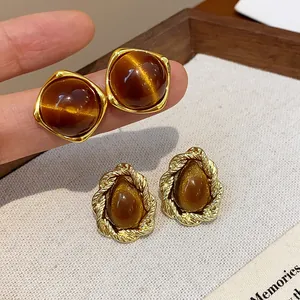 Detail view showing vintage Maillard style brown resin stud earrings with gold frames.