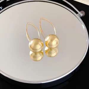 Macro view of gold sphere drop earrings featuring unique radial texture and hook design.