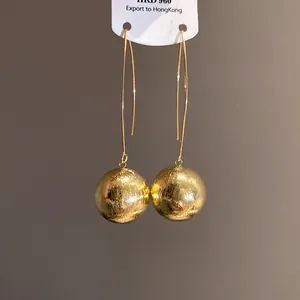Macro detail of golden round earrings with spray-painted textured finish
