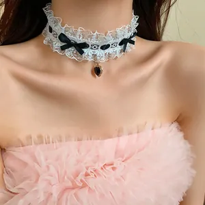 Dettaglio di un elegante girocollo in pizzo bianco con fiocchi neri e ciondolo a cuore