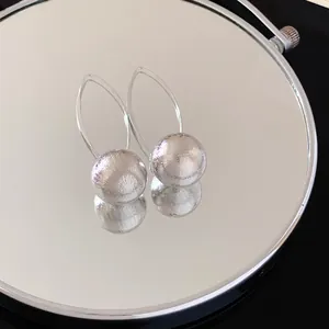 Macro detail of silver spherical earrings with radiating texture and elegant wire hooks
