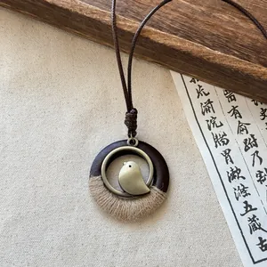 Detailed view of a Zen style round bird pendant necklace with rustic wood and twine elements