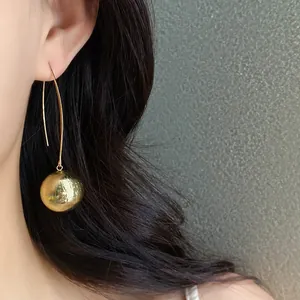Close-up of elegant gold textured sphere drop earrings with long curved ear hooks