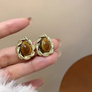 Close-up of vintage resin stud earrings with teardrop stone and gold braided border