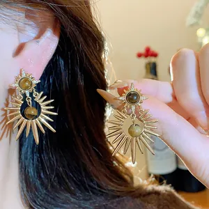 Detailed macro view of vintage sunburst earrings with tiger's eye stone and cubic zircons.