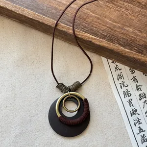 Detailed view of a vintage Zen style necklace with circular metal and dark wood pendant.